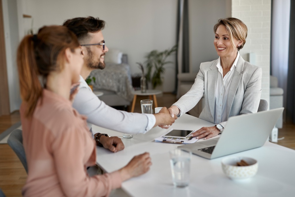 Happy real estate agent shaking hands with a couple on a meeting